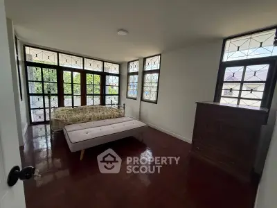 Charming bedroom with vintage windows and wooden flooring, offering a cozy and inviting atmosphere.