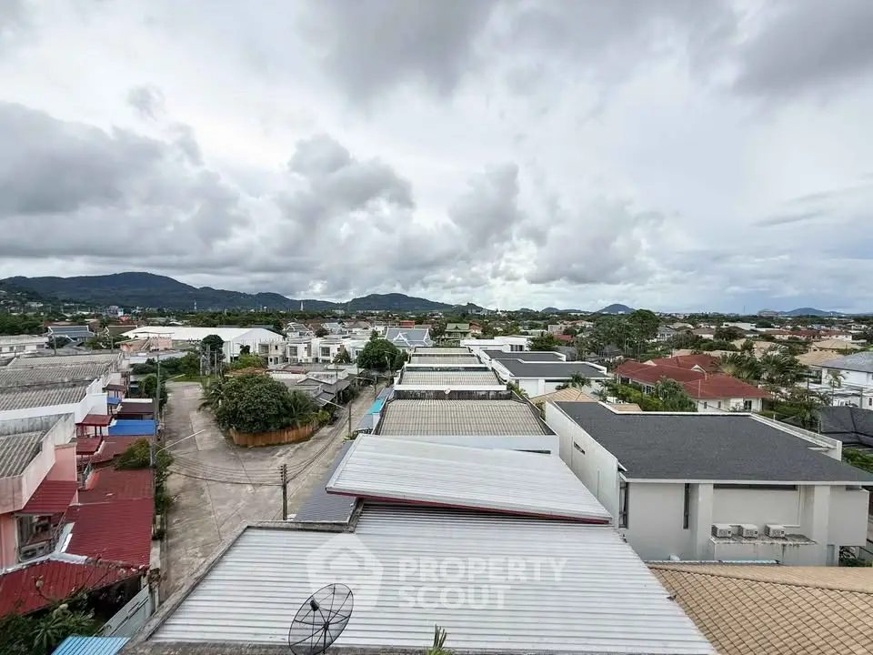 Scenic rooftop view of suburban neighborhood with mountains in the background.