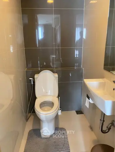 Modern bathroom with sleek design and compact layout, featuring a toilet and sink.