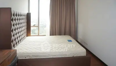 Spacious bedroom with large window and elegant headboard in modern apartment.