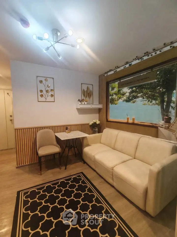 Charming living room with cozy seating and large window offering scenic views, perfect for relaxation.