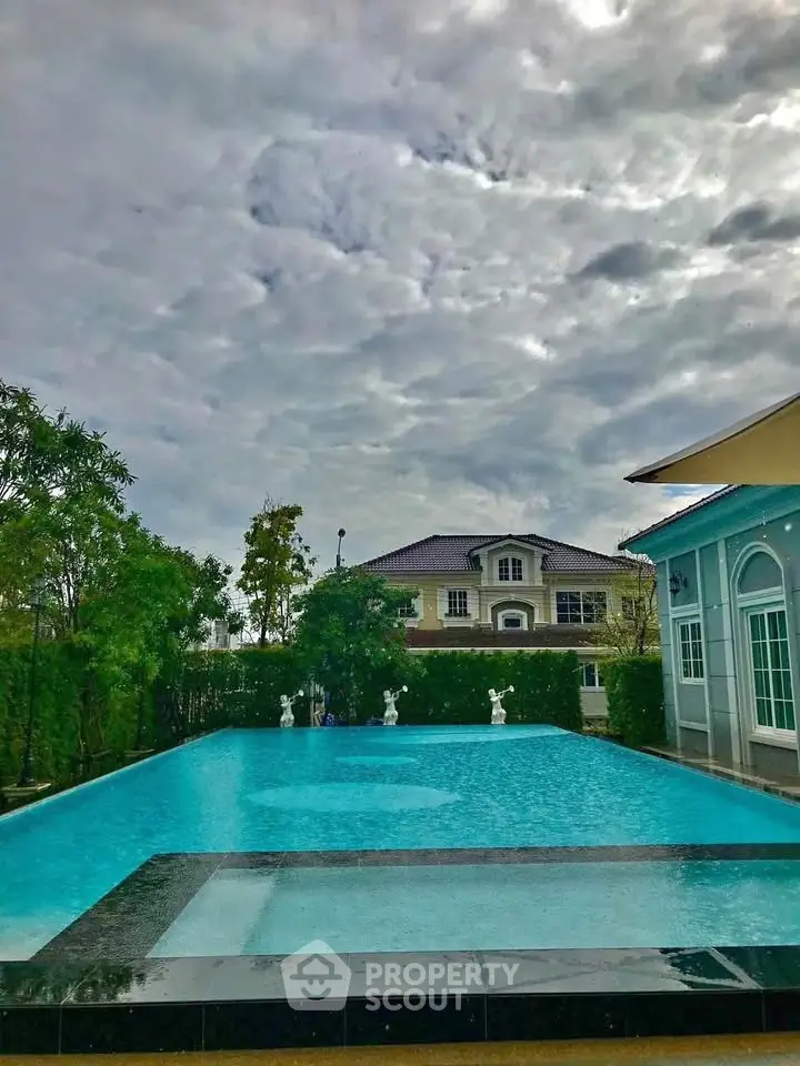 Luxurious residential pool with elegant statues and lush greenery, perfect for relaxation and leisure.