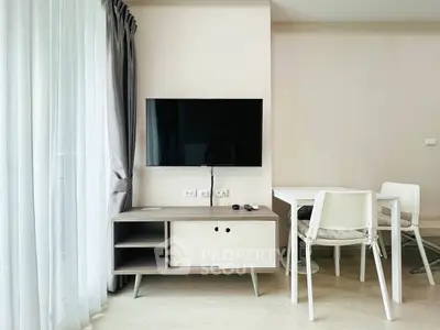 Modern living room with wall-mounted TV and dining area in stylish apartment.