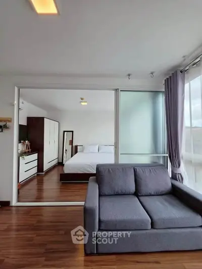 Spacious modern bedroom with sliding glass doors and cozy seating area, featuring elegant wooden flooring.