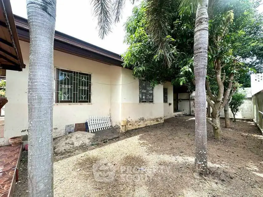 Charming single-story home with lush garden and mature trees, offering serene outdoor living space.