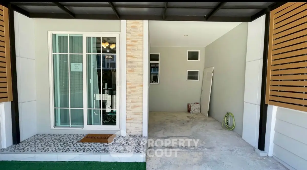 Modern house entrance with sliding glass door and adjacent garage space.