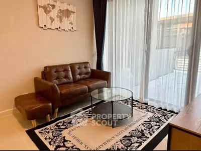 Stylish living room with leather sofa and glass coffee table, featuring floor-to-ceiling windows.