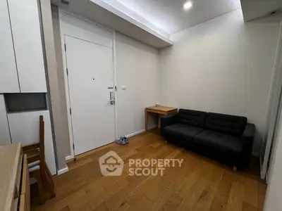 Modern apartment entrance with sleek wooden flooring and cozy seating area.