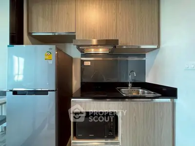 Modern kitchen with sleek appliances and wooden cabinetry in a compact layout.