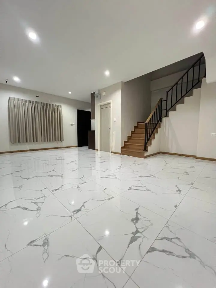 Spacious modern living room with elegant marble flooring and staircase, perfect for stylish living.