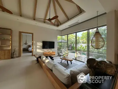 Spacious living room with modern decor and garden view, featuring high ceilings and natural light.