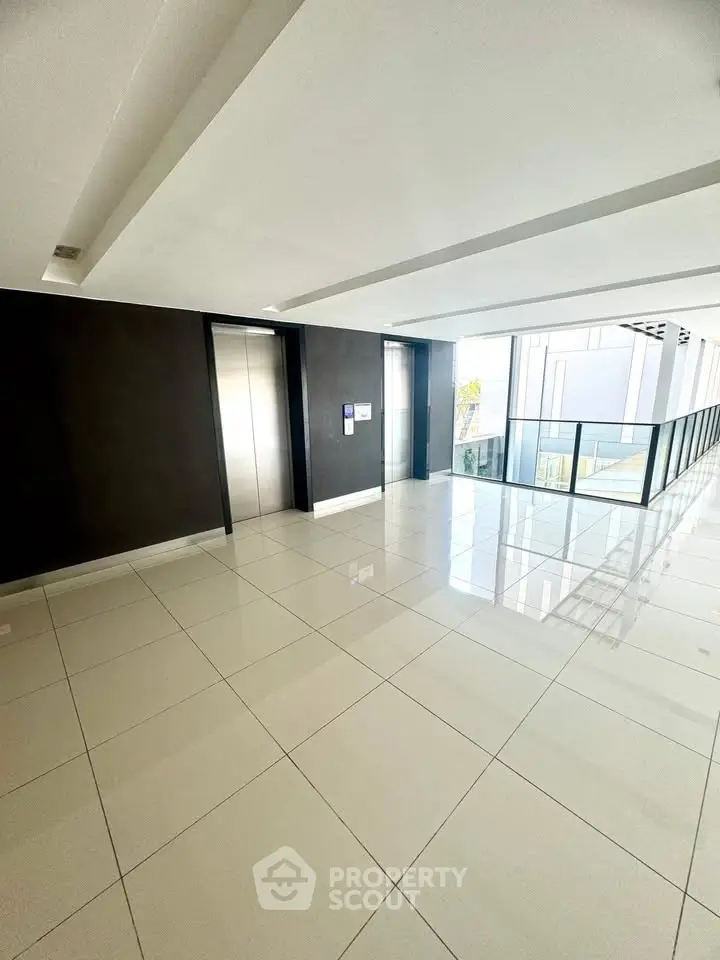 Modern building elevator lobby with sleek design and glossy tiled floors.