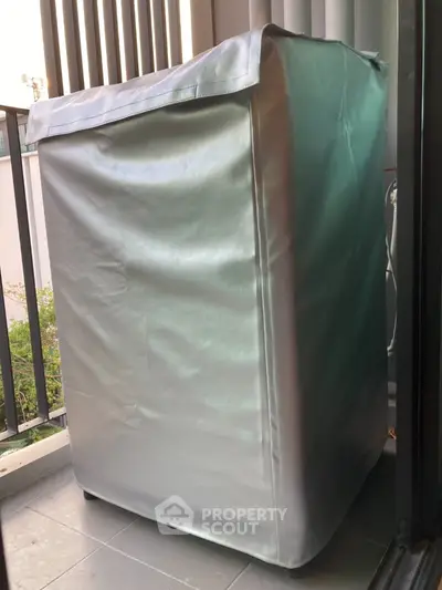 Covered washing machine on a balcony with railing view