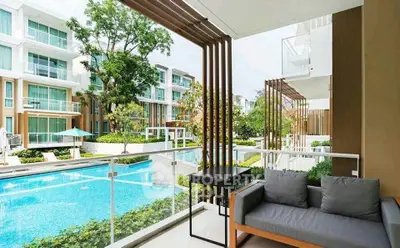 Luxurious balcony view overlooking a pristine pool and modern apartment complex, perfect for relaxation.