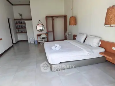 Spacious bedroom with modern decor and natural lighting, featuring a comfortable bed and stylish furnishings.