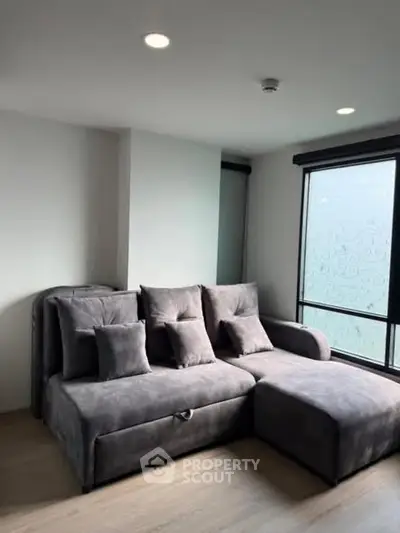 Modern living room with stylish gray sectional sofa and large window.