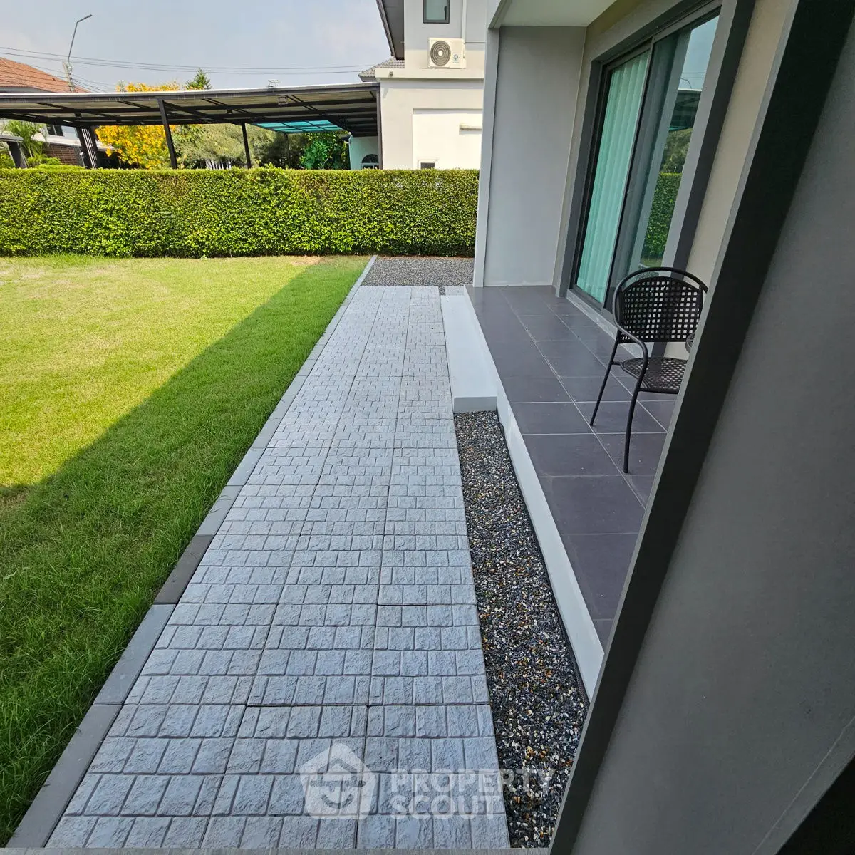 Modern home exterior with sleek patio and lush green lawn, perfect for outdoor relaxation.