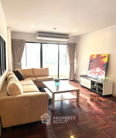 Spacious living room with large windows and modern decor in a high-rise apartment.