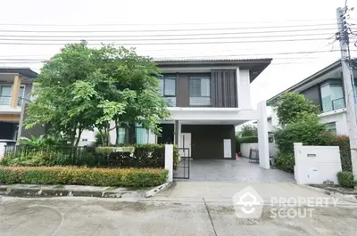 Modern two-story house with a spacious garage and lush greenery, featuring a sleek design with large windows and a cozy, welcoming entrance.