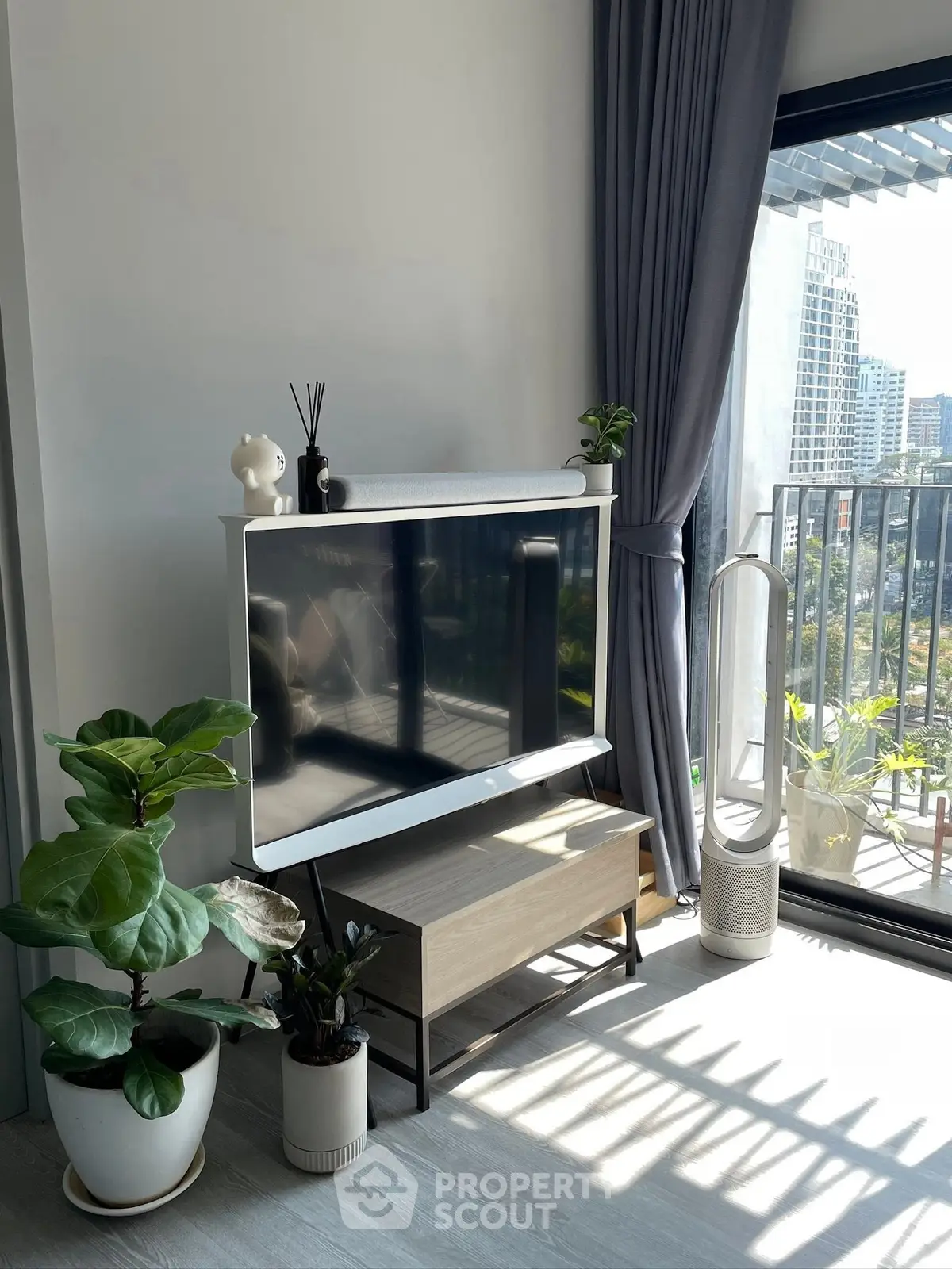 Modern living room with large TV, stylish decor, and balcony view in urban apartment.