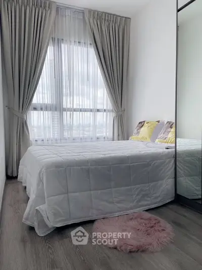Cozy bedroom with large window and elegant curtains, featuring a plush bed and mirrored wardrobe.