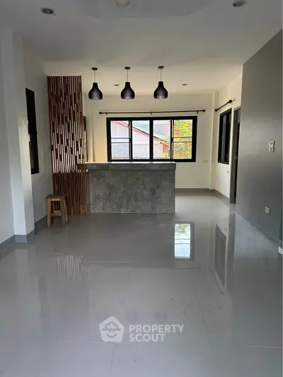 Spacious modern living room with stylish lighting and large windows offering natural light.