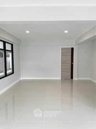 Spacious empty room with large windows and modern tile flooring