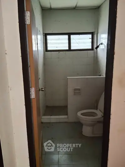 Compact bathroom with basic fixtures and natural light from window.