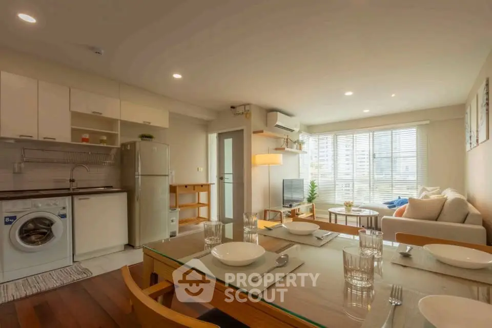 Spacious modern living room with open kitchen and dining area, featuring natural light and stylish decor.