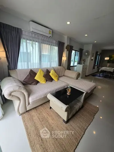 Spacious living room with elegant sofa and natural light, perfect for relaxation and entertaining.