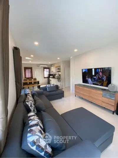 Spacious living room with modern decor and open layout, featuring a cozy seating area and entertainment center.