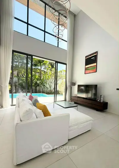Luxurious living room with high ceilings, large windows, and pool view, perfect for modern living.