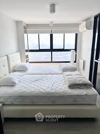 Spacious bedroom with twin beds and panoramic city view, featuring modern decor and ample natural light.