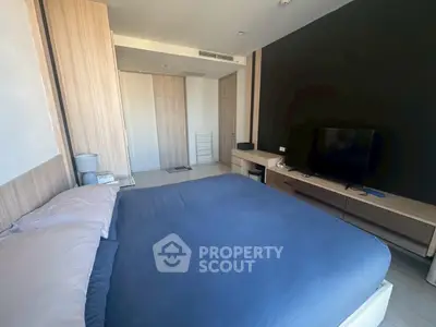 Spacious modern bedroom with sleek design and large TV, perfect for relaxation.