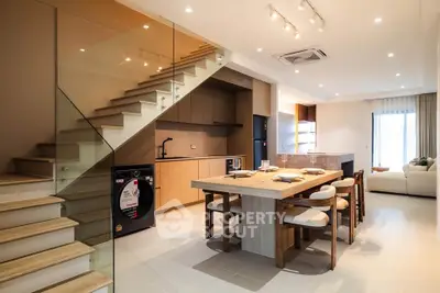 Modern open-plan kitchen and dining area with stylish staircase and cozy living room.
