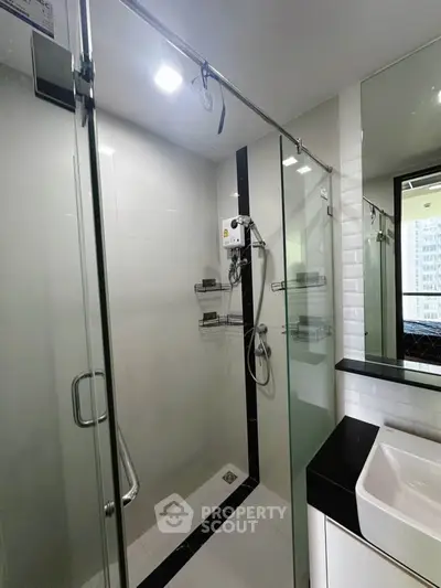Modern bathroom with glass shower enclosure and sleek fixtures in a contemporary apartment.