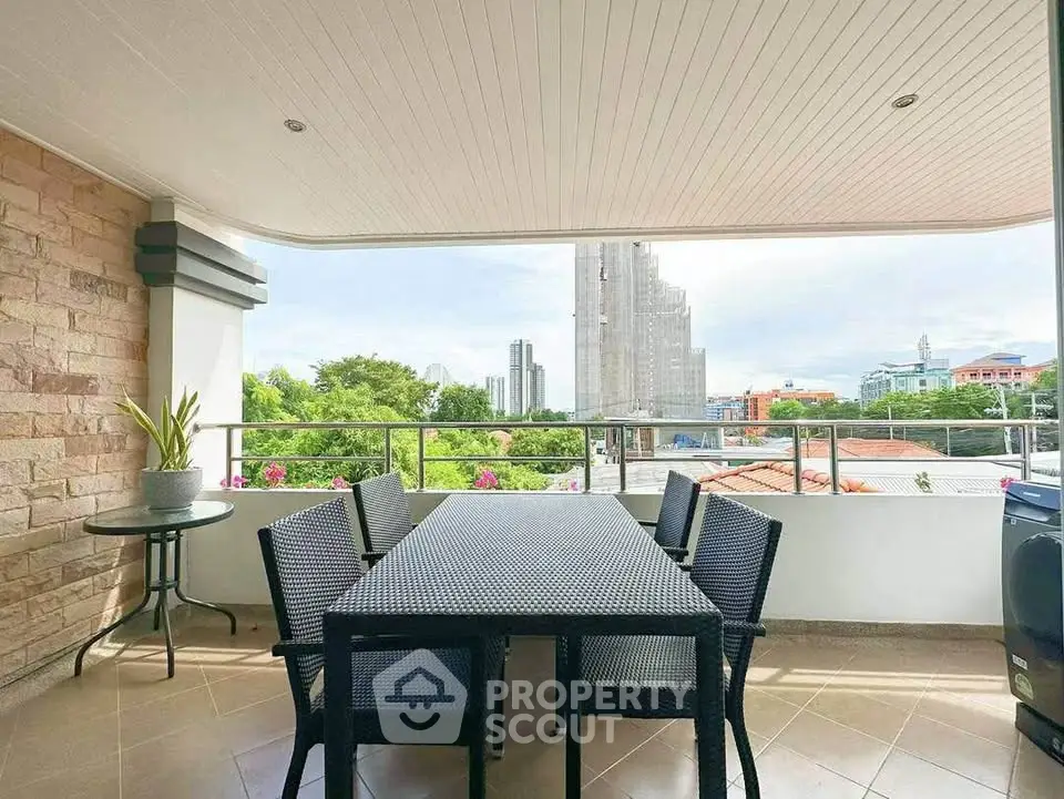 Spacious balcony with outdoor dining set and city view, perfect for relaxation and entertaining.