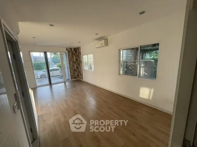 Spacious empty living room with wooden flooring and large windows