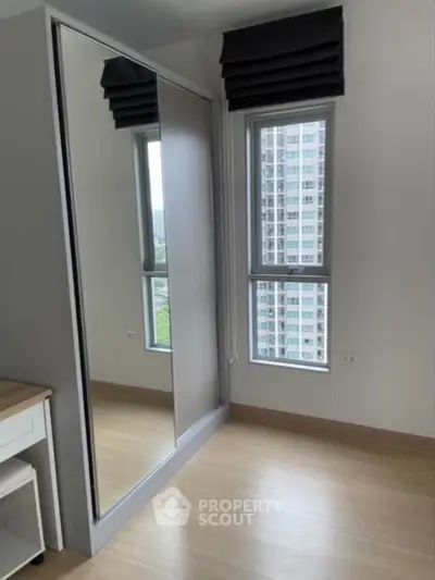 Modern bedroom with mirrored wardrobe and city view window
