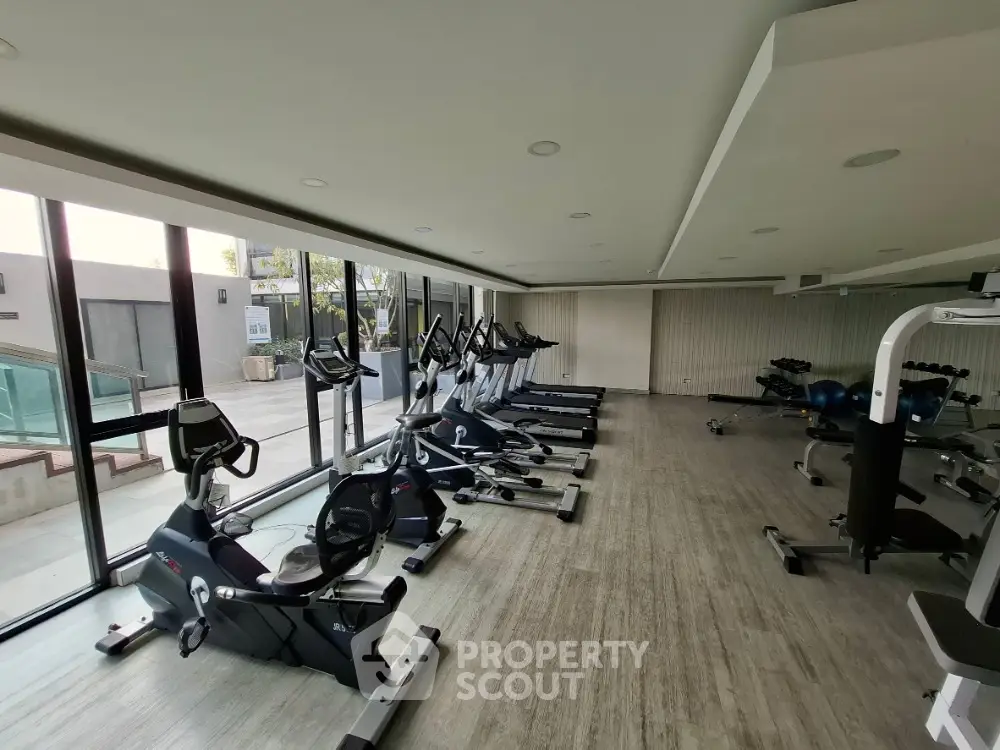 Modern gym with state-of-the-art exercise equipment and large windows in luxury real estate property.