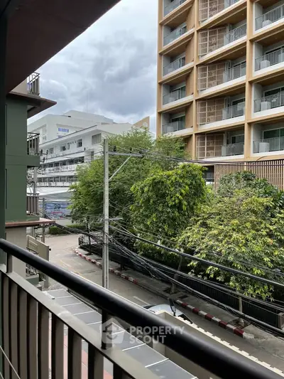 Urban balcony view with modern buildings and lush greenery