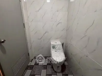 Modern bathroom with marble tiles and sleek toilet design.