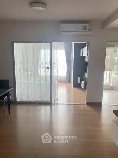 Spacious modern living room with wooden flooring and large windows for natural light.