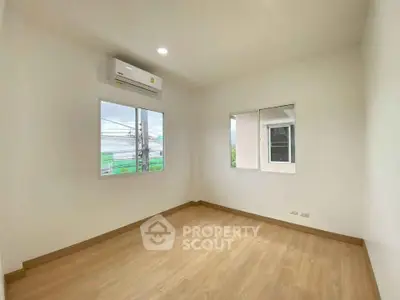 Spacious empty room with wooden flooring and air conditioning, perfect for customization.