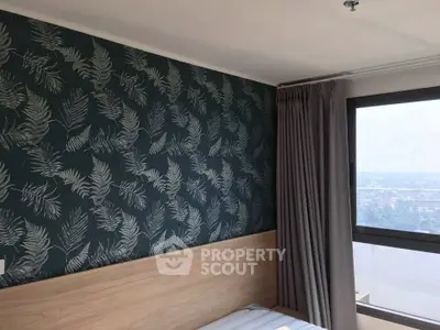 Stylish bedroom with leafy wallpaper and large window offering scenic views.