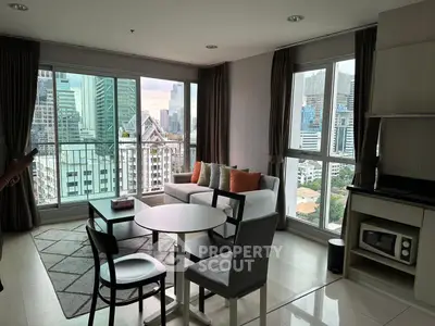 Modern living room with city view, stylish furniture, and large windows in high-rise apartment.