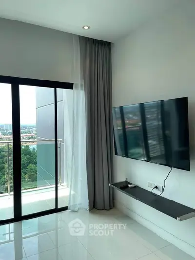 Modern living room with balcony and city view, featuring sleek TV setup.