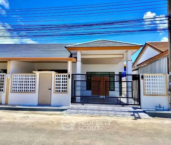 Modern single-story house with sleek design and gated entrance under a clear blue sky.