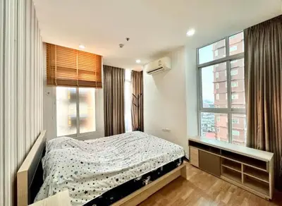 Spacious bedroom with large windows and modern decor in a high-rise apartment.