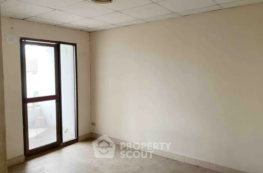 Spacious empty room with large window and balcony access, ideal for customization.